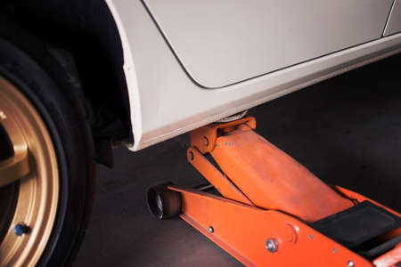 Car Lifted with blue hydraulic floor jack for repairing.の写真素材