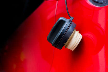 Close up shot of a car's. Open fuel tank lid in red car. Refueling a car at a fuel station.の写真素材