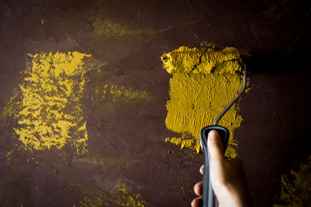 The house painter hand is painted yellow on the old brown wall with copy space.
