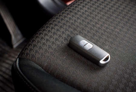Car keyless remote on a fabric car seat in a luxury car.