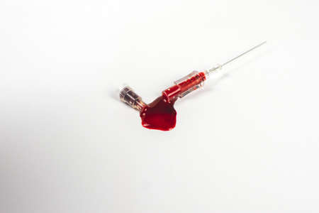 Blood out leaked from the medical syringe needle on a white paper background.の写真素材