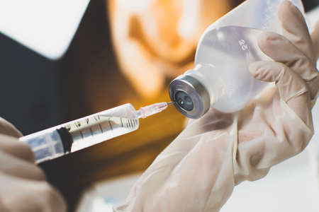Anesthesiologist Doctors hand inject syringe into normal saline solution (NSS) bottle.の写真素材