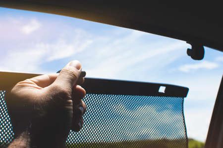 Driver is lifting car side window curtains sunshades for sunlight protectの写真素材