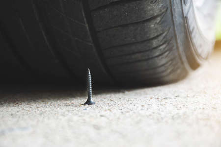 Close up of sharp metal screw on road nearly to puncture a car tireの写真素材