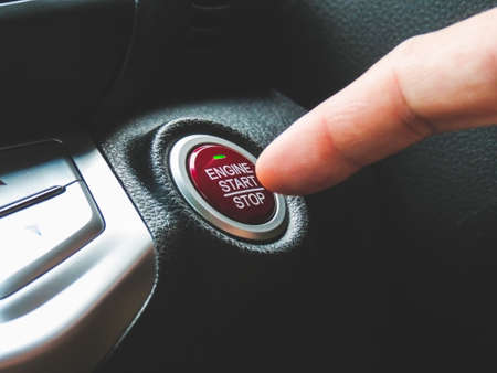 Car driver press to the engine start stop button for engine ignition in a luxury car