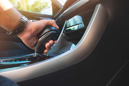 The driver's hand holds the gear lever of the automatic transmission in the car