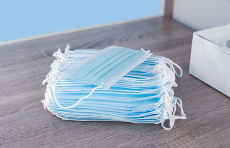 Disposable face mask pile on the wooden table, Coronavirus (COVID-19) and influenza infection...