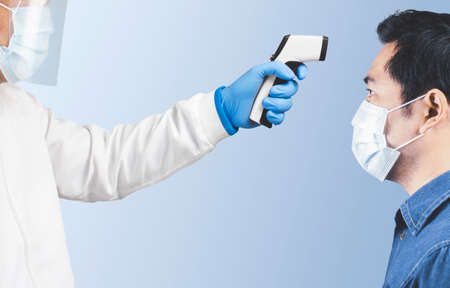 The doctor is measuring the patient's temperature with an infrared thermometer