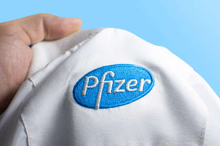 Rayong,Thailand - Jan 23, 2021: Pfizer Biontech logo on white shirt in a hand on blue color...
