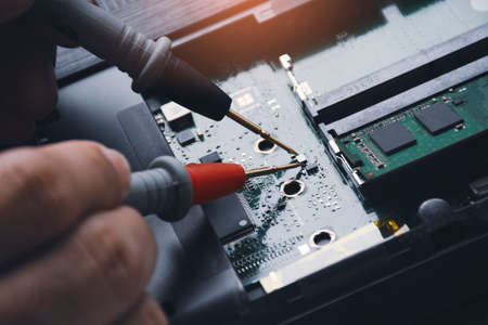 Technician checking laptop circuit board with multimeterの写真素材