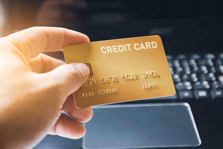 Credit card premium in the hand with computer keyboard background