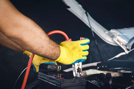 Technician clamping the charger cable to the car battery,accumulator charging
