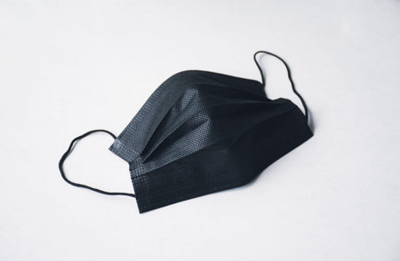 Black surgical face mask with ear strap on white background