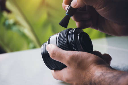 Human hand cleaning dust on camera lens with pen brush cleanerの写真素材