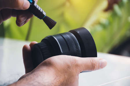 Human hand cleaning dust on camera lens with pen brush cleanerの写真素材