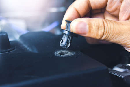 Mechanic hand installing automotive plastic fasteners to the car body in the auto repair garageの写真素材