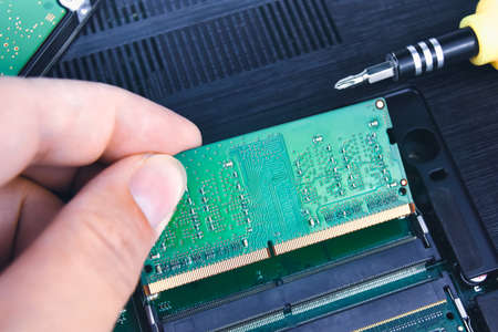 A technician installs a RAM in a laptop computer (Random Access Memory)