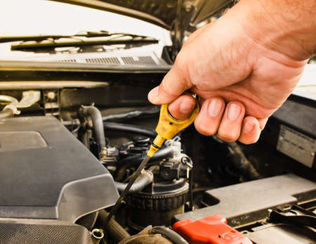 Mechanic hand pulling up oil dipstick of the car engine for checking oil level