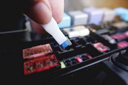 Mechanic replaces the spare fuse to the car fuse box with the fuse clip toolの写真素材