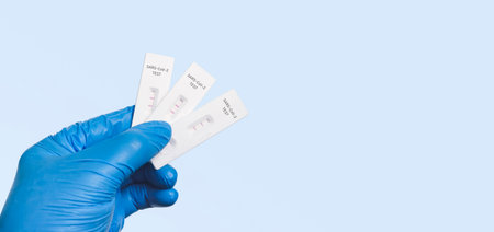 The doctor showing positive test result with SARS CoV-2 Rapid antigen test kit (ATK), isolated on blue background with copy space,infectious protective conceptの写真素材