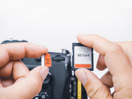 Memory micro SD and SD cards are compared for usage with digital DSLR cameras in the hands of a...