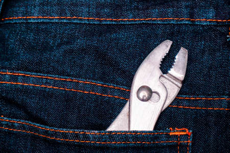 Metal pliers in the back denim pocket of mechanic man