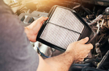 A auto mechanic carries a replacement car air filter for car engine maintenanceの写真素材
