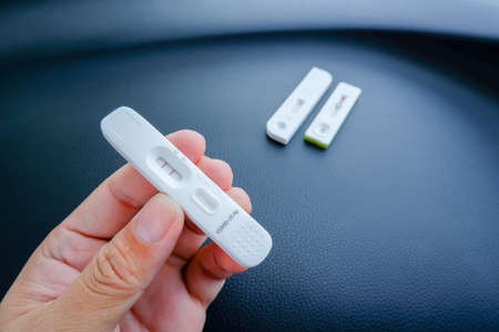 Covid-19 Test cassette with positive result on the hand,Coronavirus infectious protective conceptの写真素材