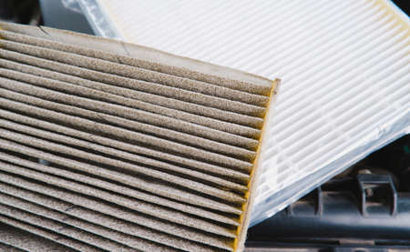Car air filter clogged and new air filter in a plastic wrapped on background
