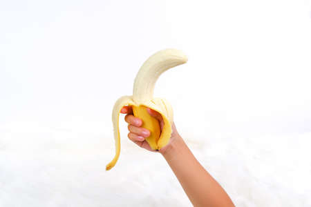 Peeled, ripe cavendish banana in human hand, Object isolated on white background, Healthy fruit nutrition conceptの写真素材