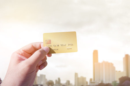 Close up of male hand holding credit card on blurred cityscape background, Shopping and travel conceptの写真素材