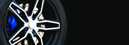 Closeup of the wheel of a sports car on a black background, panoramic banner with copy spaceの写真素材