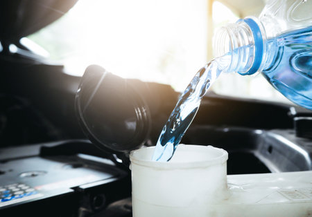 Close up of a bottle of water being poured into a windshield washer tank.の写真素材