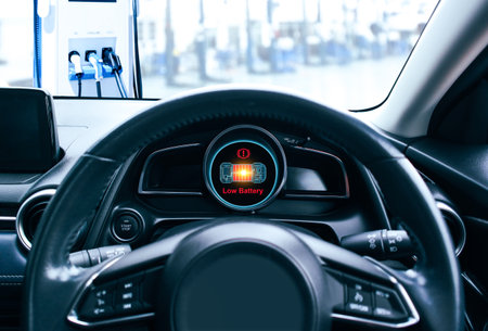 Low battery caution display on screen of a electric car instrument panel, The battery voltage signal is dropping and low, electric car parked on EV charger station, Electric vehicle technology conceptの写真素材