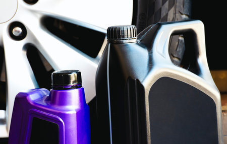 Engine oil gallon and motor oil bottle with a grey car wheel on background Car maintenance conceptの写真素材