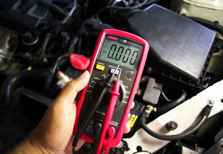 Digital multimeter in the hands of mechanics for measuring car electrical systems , Car maintenance service conceptの写真素材