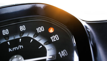 Check Engine Light On, Closeup of a motorcycle speedometer showing an illuminated orange check...