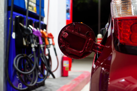 Modern Gas Station Service, An open red car fuel door sits in the foreground at a gas station, with...