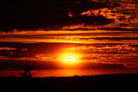 red evening sky with sun and cloudsの写真素材
