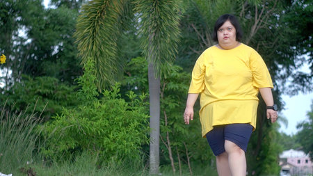 Asian woman with down syndrome walking for exercise in the park.の写真素材