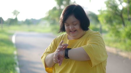 Asian girl with Down syndrome watching the clock while exercising at the park.の写真素材