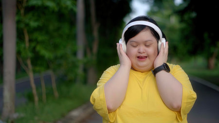Down syndrome girl exercising in the park wearing headphones.の写真素材