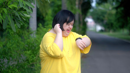 Looking at the clock, an Asian girl with Down syndrome rejoices.As I exercised in the park.の写真素材