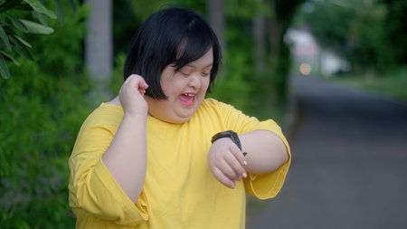 Looking at the clock, an Asian girl with Down syndrome rejoices.As I exercised in the park.の写真素材