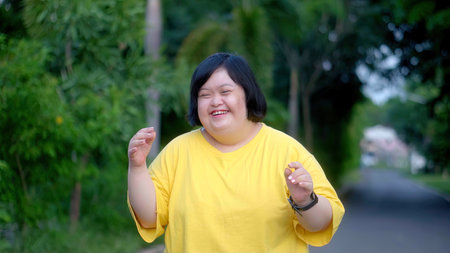 Looking at the clock, an Asian girl with Down syndrome rejoices.As I exercised in the park.の写真素材