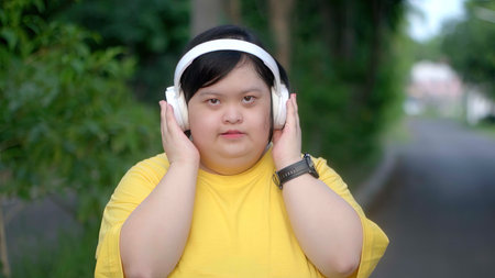 Down syndrome girl exercising in the park wearing headphones.の写真素材