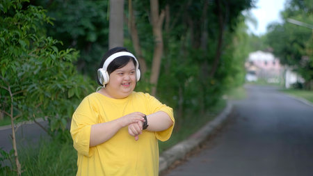 Down syndrome watching the clock and headphones while exercising at the park.の写真素材
