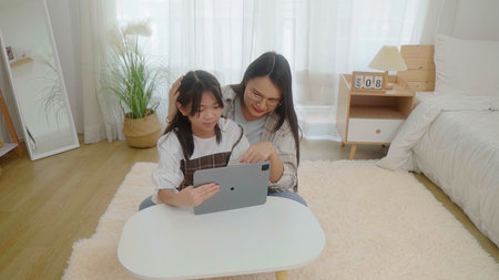 Asian little young girl learning online class at home with motherの写真素材