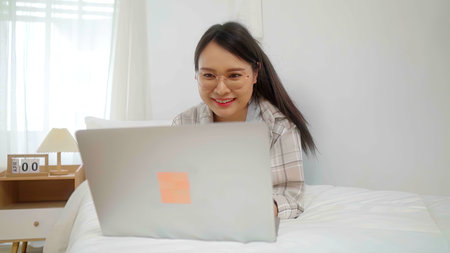 Asian freelance business woman using laptop online business  in bed at home.の写真素材