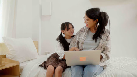 Asian little young girl learning online class at home with mother.の写真素材